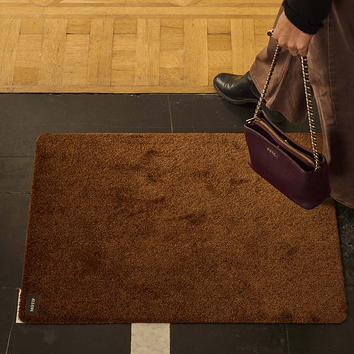A woman who is holding a bag is walking on a floor mat