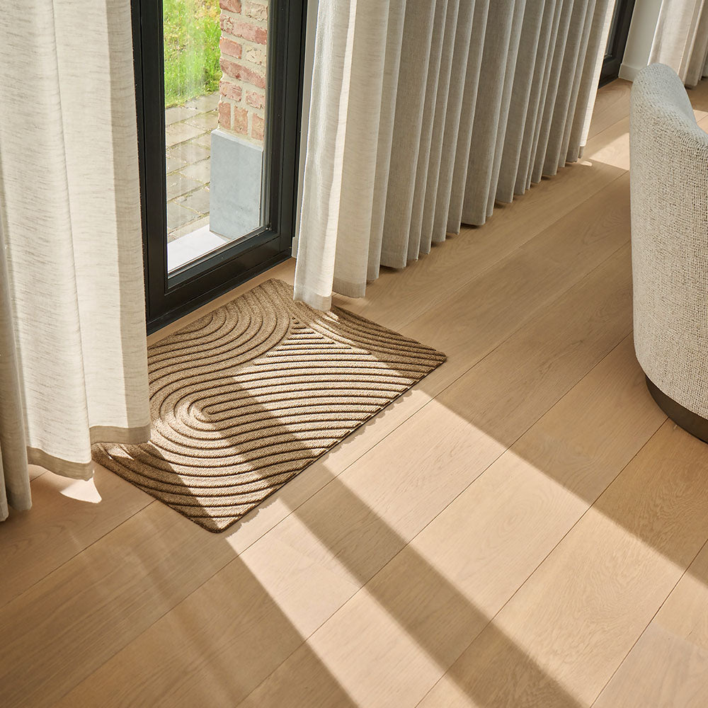 Lifestyle photo showing WaterHog All-Weather Indoor Outdoor Floor Mat in use at a door with curtains inside a nice and cosy interior design home in beige and warm tones