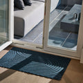 Lifestyle photo showcasing WaterHog All-Weather Indoor Outdoor blue navy marine colour Floor Mat in use in front of door at a terrace with a seat and pillows and an open door